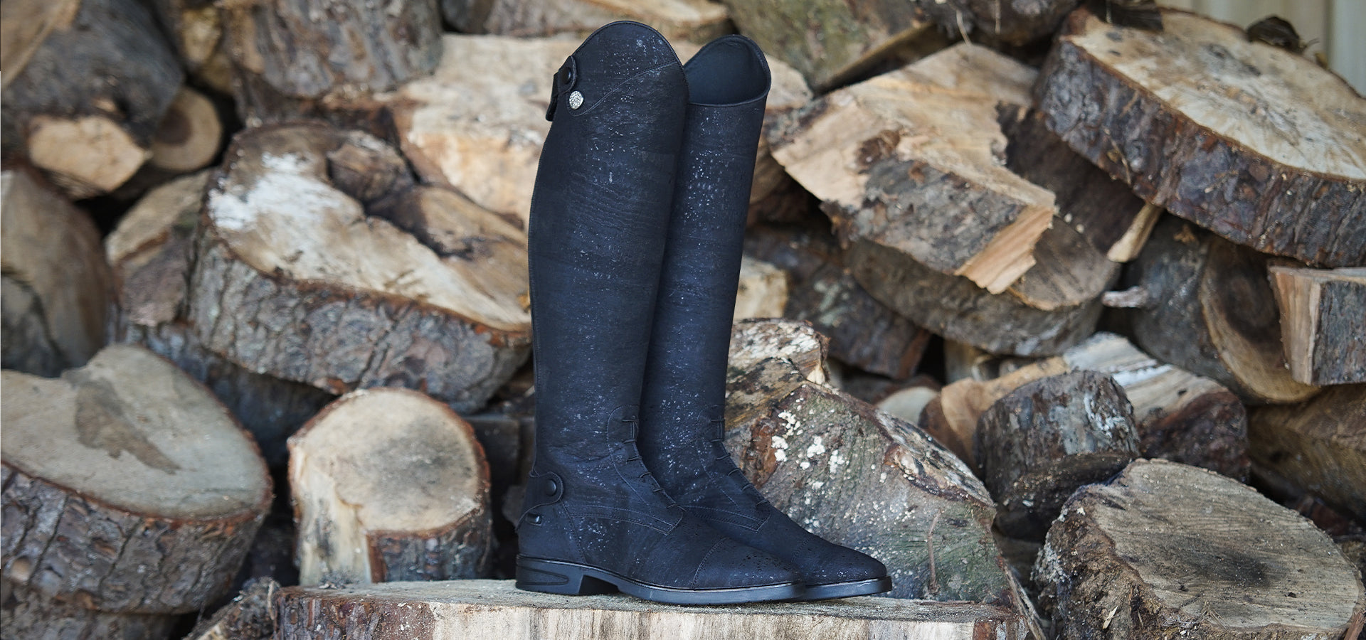 Equestrian cork riding boot displayed on top of a wooden stump